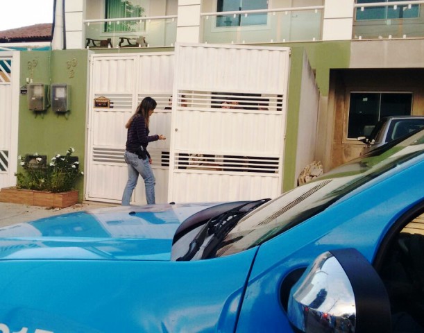 Uma inspetora da Polícia Civil entrando na casa para levantar pistas
