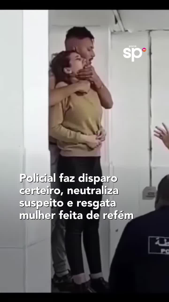 Homem mantém mulher junto ao corpo enquanto policiais acompanham a ocorrência