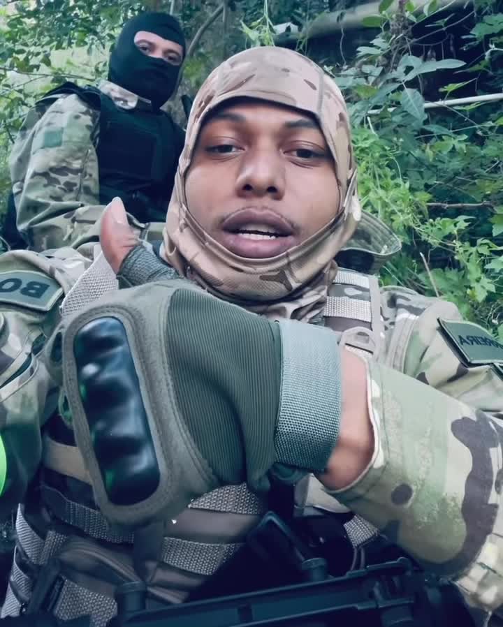Homem faz gesto enquanto grava mensagem em área de vegetação